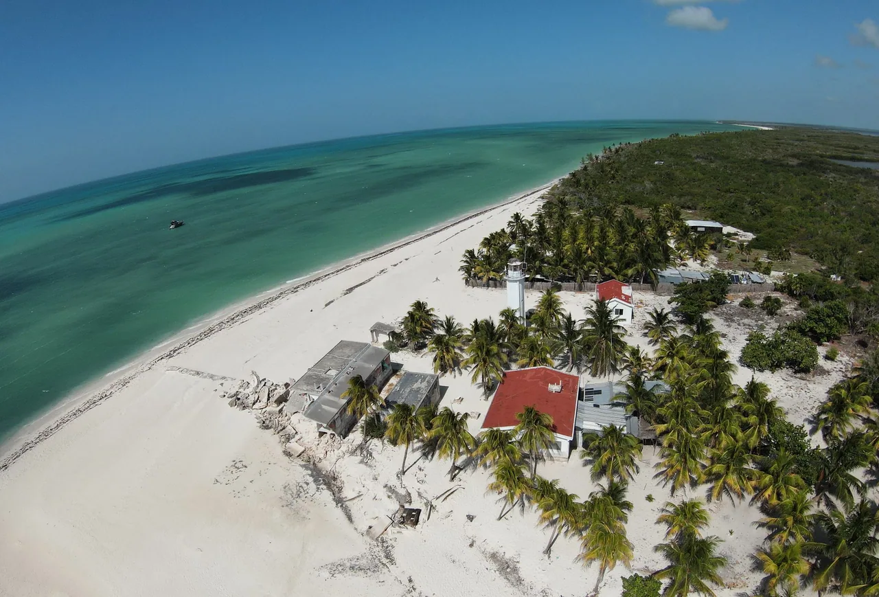 Playa de arena blanca con faro y palmeras en Isla Holbox, vista aérea